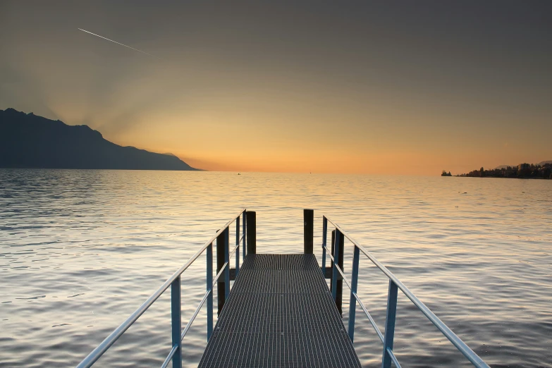 a jetty on the water with an airplane flying above it