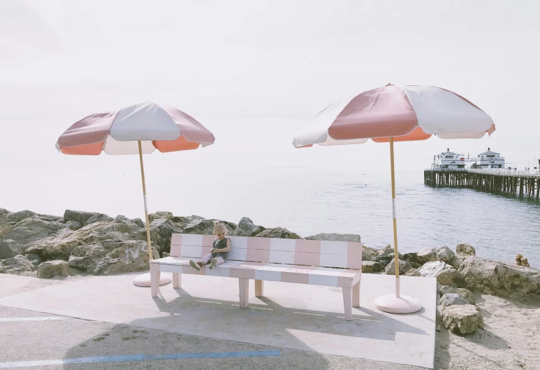 some tables with umbrellas sitting on the rocks by the water