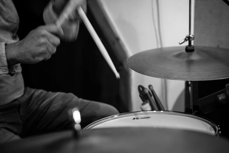 black and white pograph of a man holding two sticks over drum kit