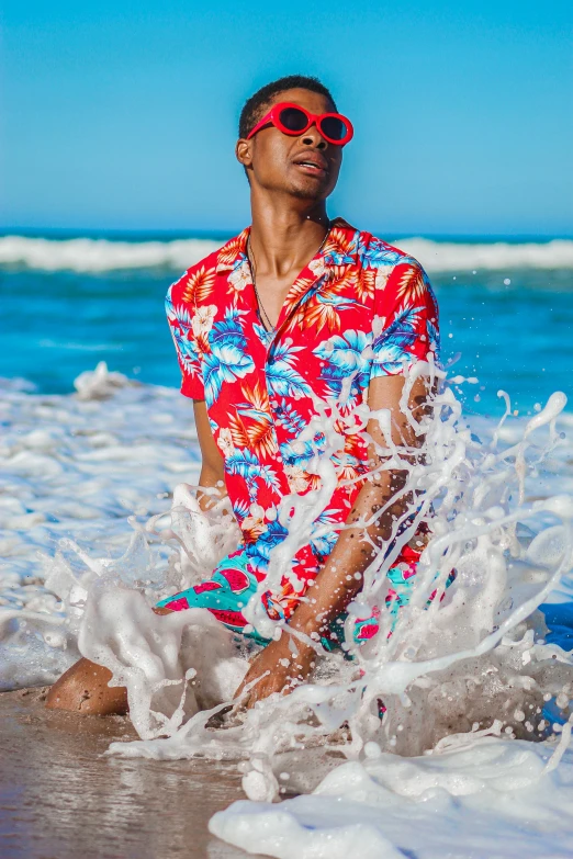 man with sunglasses sitting in the surf splashing about