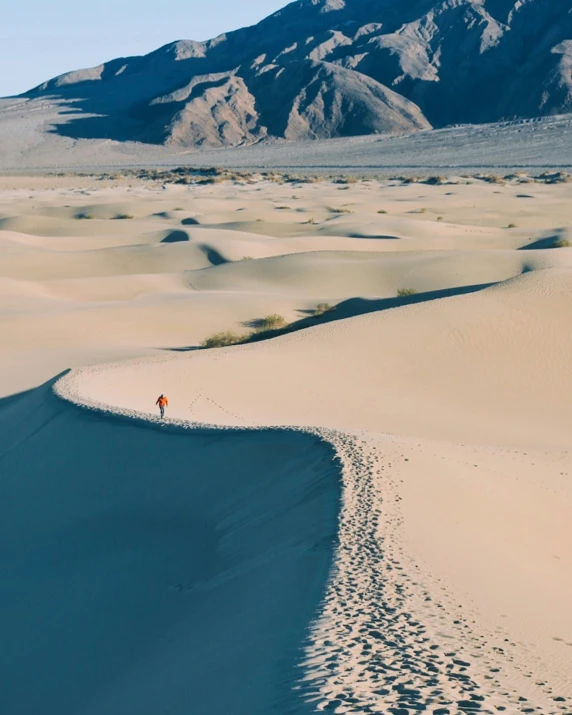 a person walking across sand in a desert area