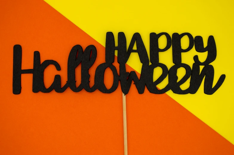 a sign that says happy halloween is written with black felt on an orange yellow and yellow background