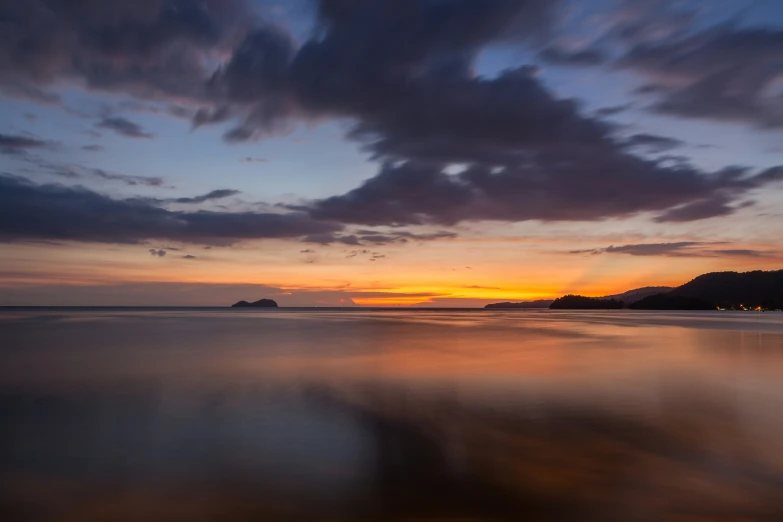 the sky is reflected in the wet sand at dusk