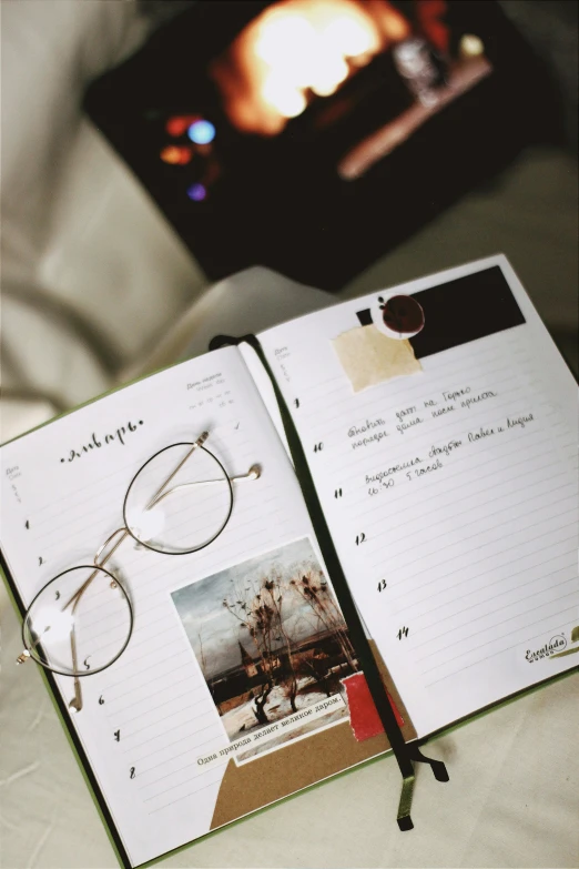an open notebook with an image and a pair of glasses on it