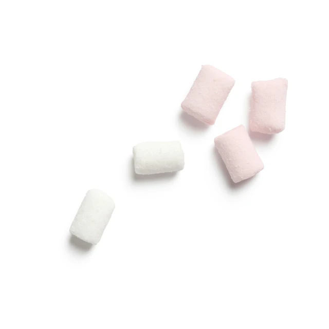 pink marshmallows are lined up on the white surface
