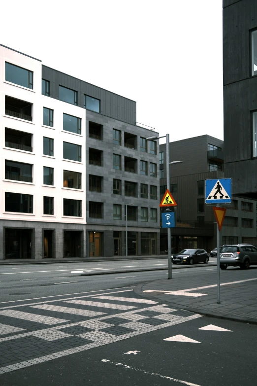 an empty street with parked cars and street signs in front of buildings