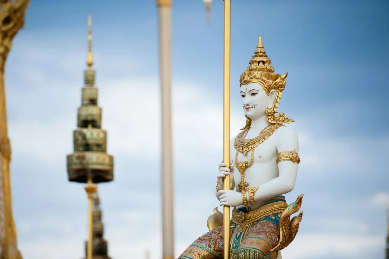 a statue of a thai god holding a pole