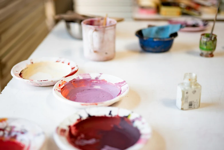 three dirty dishes sitting on a table with paint