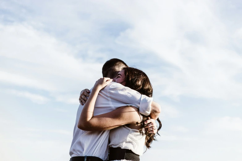 the woman hugs the man who is standing up on the ledge of the building