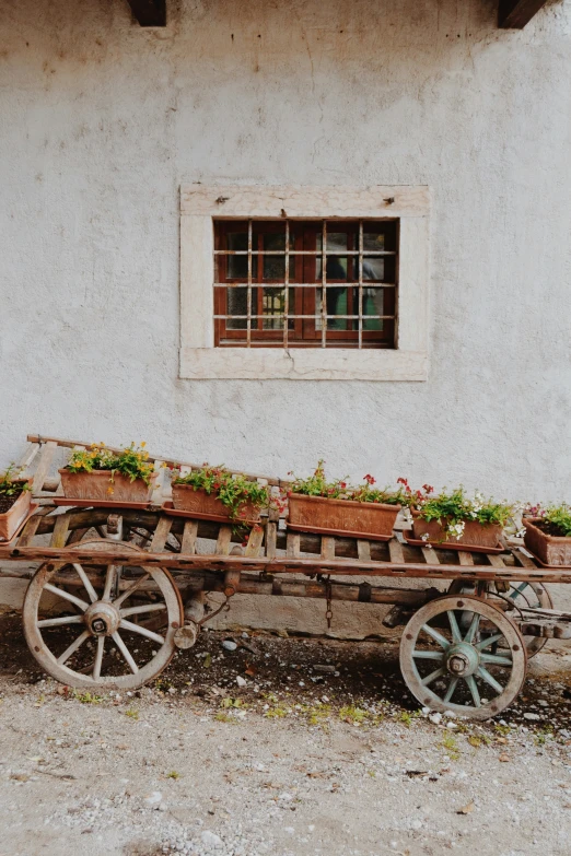a wagon with plants inside of it sitting outside of a building