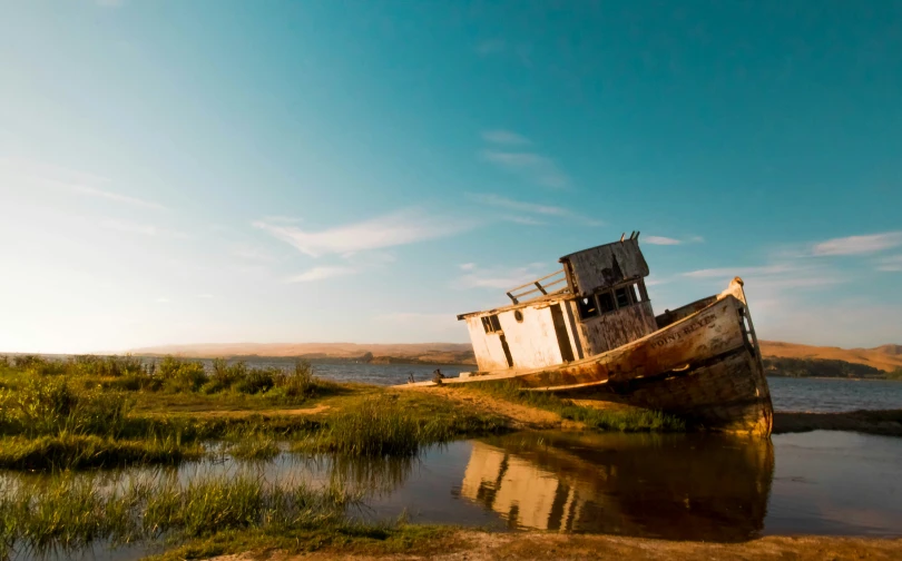 an old, abandoned boat sitting on the shore