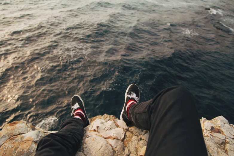 someone standing on a rock next to the ocean