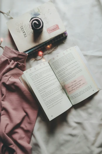 a book, glasses and a purse lying on top of a bed