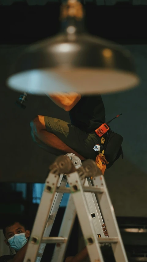 a man in black shirt working on a metal light