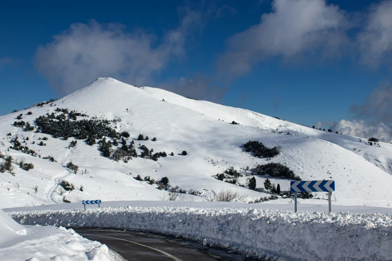 the road is winding in front of a snowy mountain