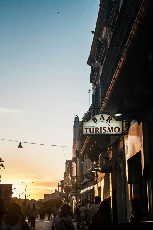 people walk down an urban street during the sunset