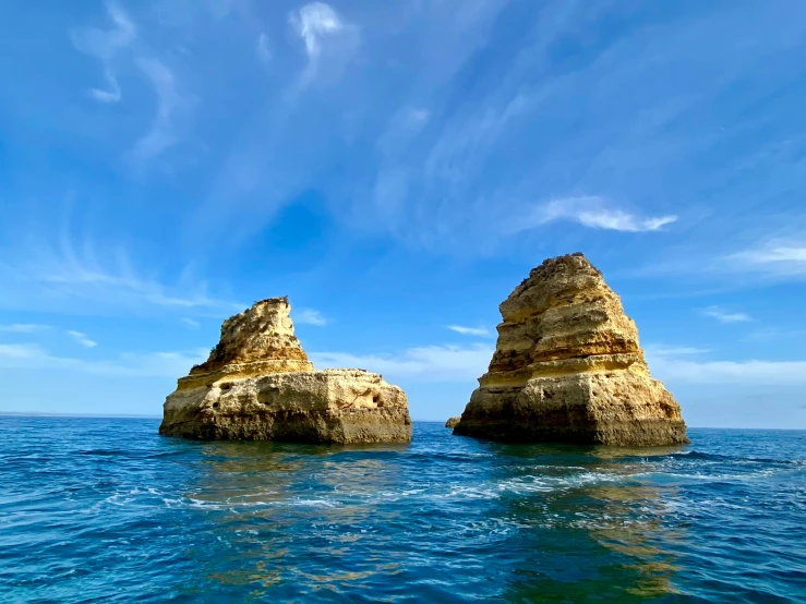 large rocks on the beach, one has a person in it