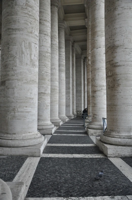 a walkway in a large stone building with columns