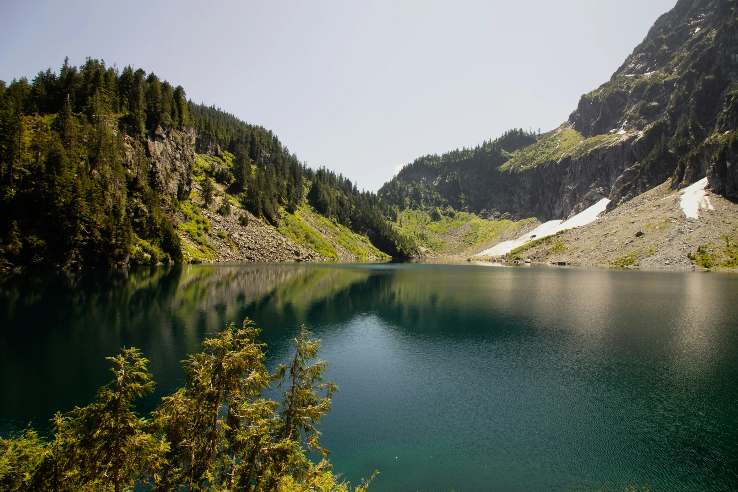 a blue lake surrounded by tall mountains with snow