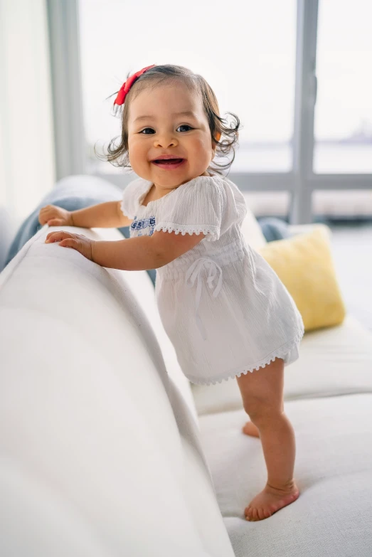 an adorable little girl standing on a couch