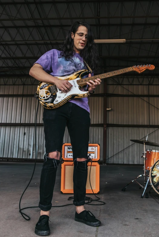 a person standing holding a guitar near two instruments