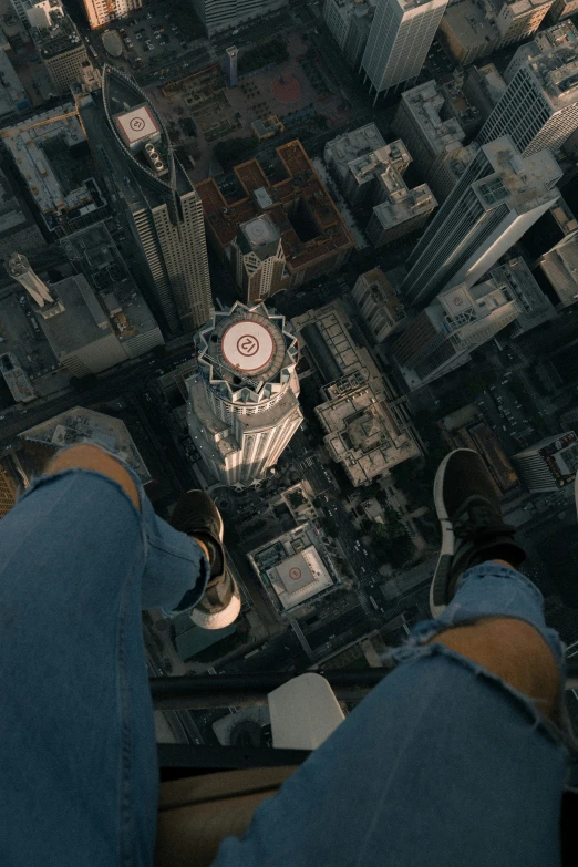 view from the floor of a high building of a cityscape with buildings, including a spiral staircase, and people