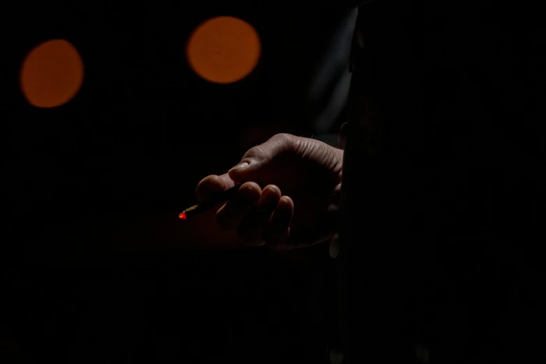 a hand holding a lighter at night with bright spots on the sky