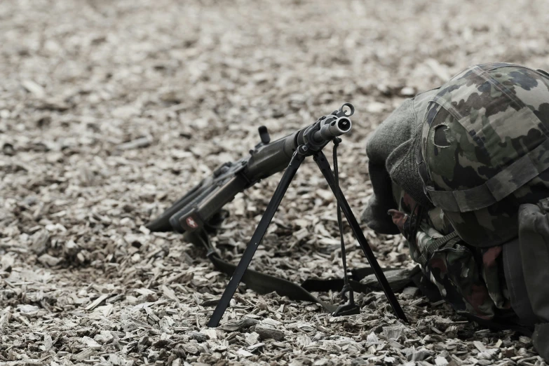 a soldier kneeling down while looking at a machine gun