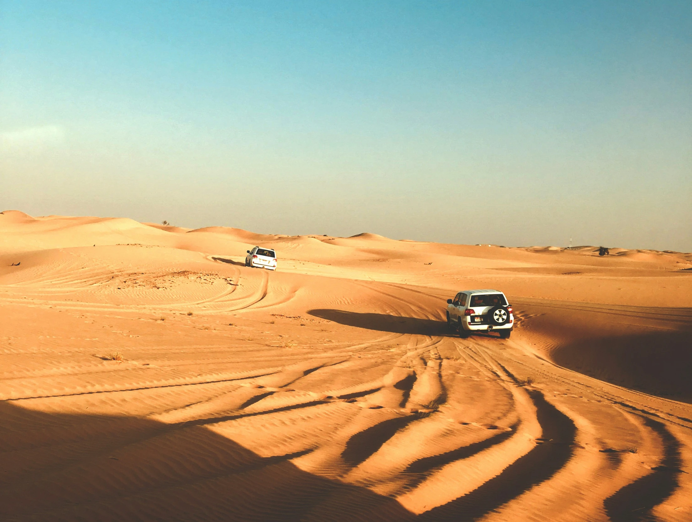 the truck is driving down a sandy road