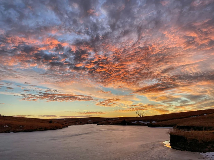 sunset with a large body of water and cloudy skies