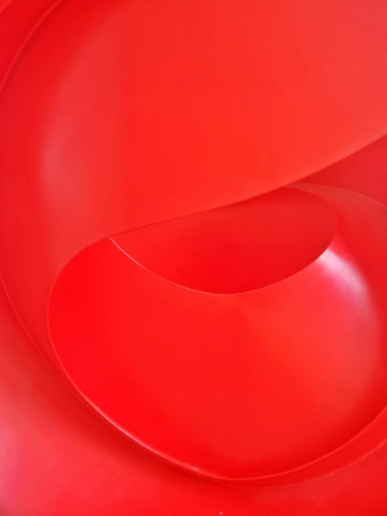 a red abstract sculpture is pictured in this po