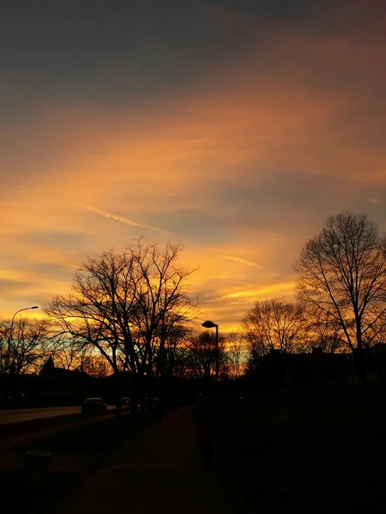 sunset in the sky over trees and a bench