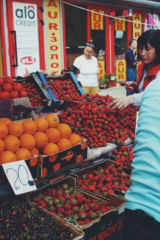 an asian woman looking at fresh berries at a market