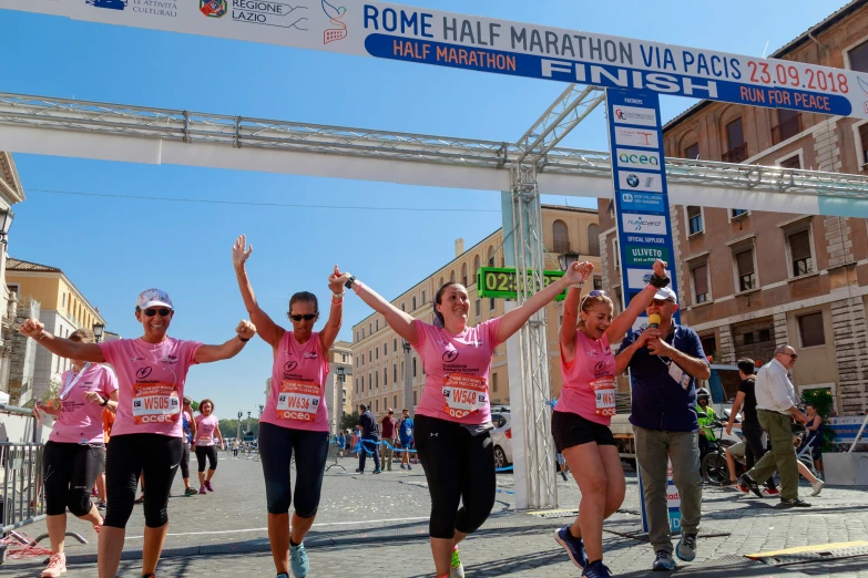 four women on the finish line holding their hands up