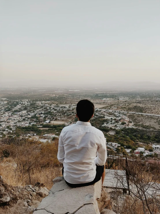 a person sitting down at the top of a cliff