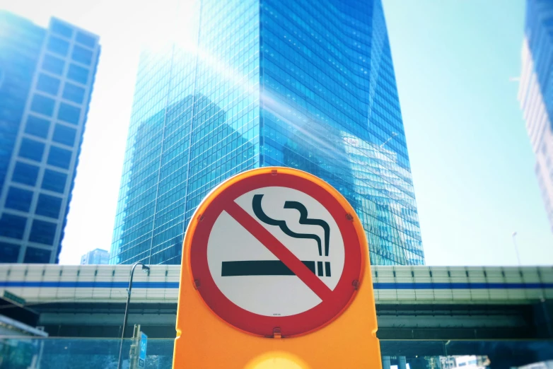 no smoking sign and an underpass with buildings in the background