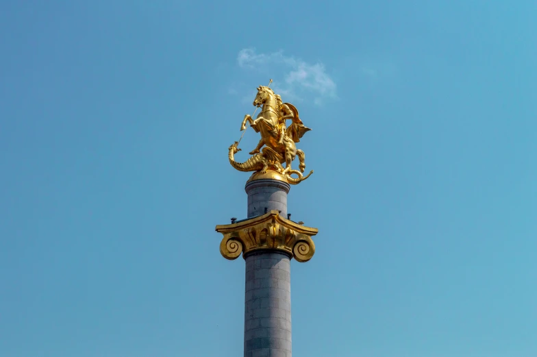 a tall pillar with a gold sculpture on it