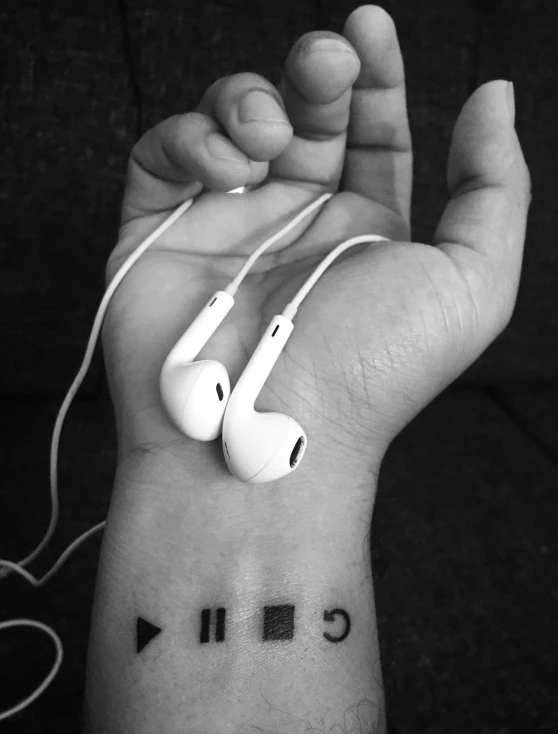 a woman wearing a white headphones is showing off her wrist tattoo