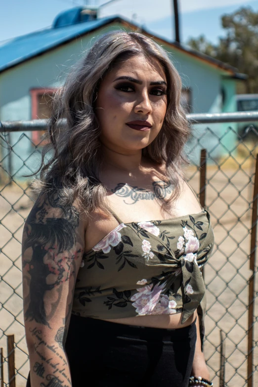 a person with tattoos is standing by a fence