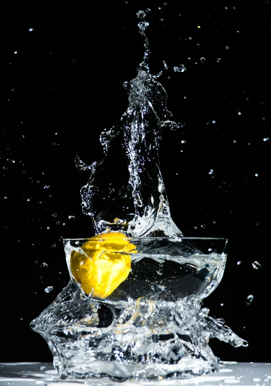 the orange dropped in the glass bowl, which is almost transparent and appears to be half - filled with water