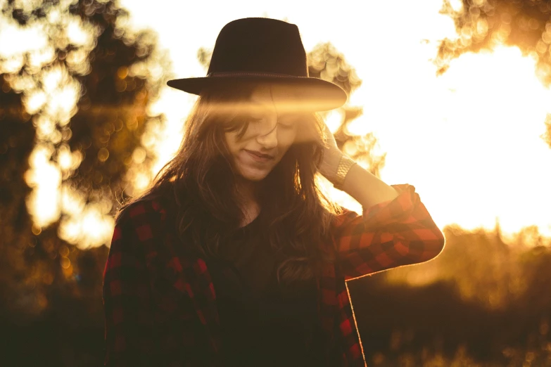 the woman is wearing a black hat and posing for the camera