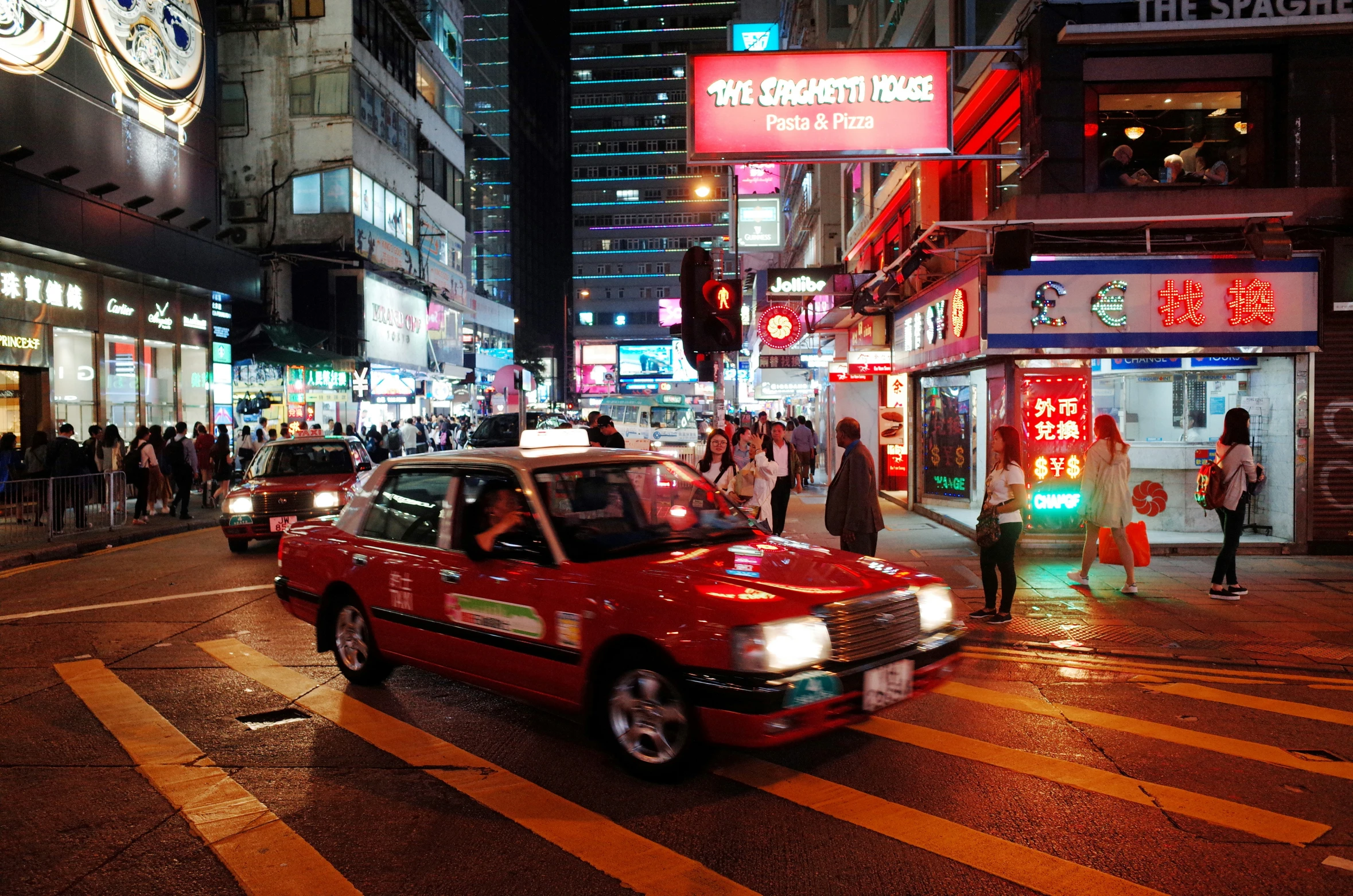 cars wait at an intersection in a city at night