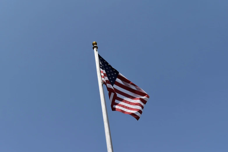 a flag flying high in the air with a blue sky behind it