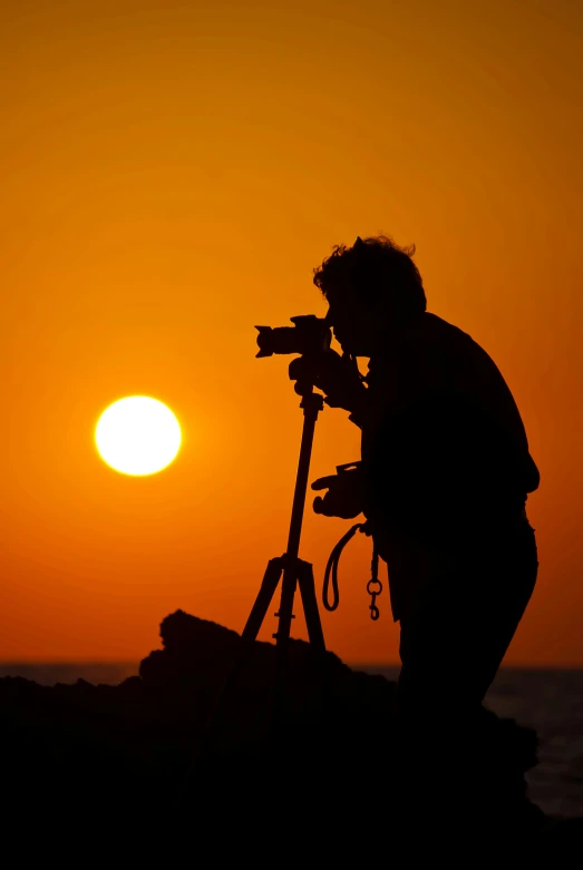a person taking pos with a tripod at sunset