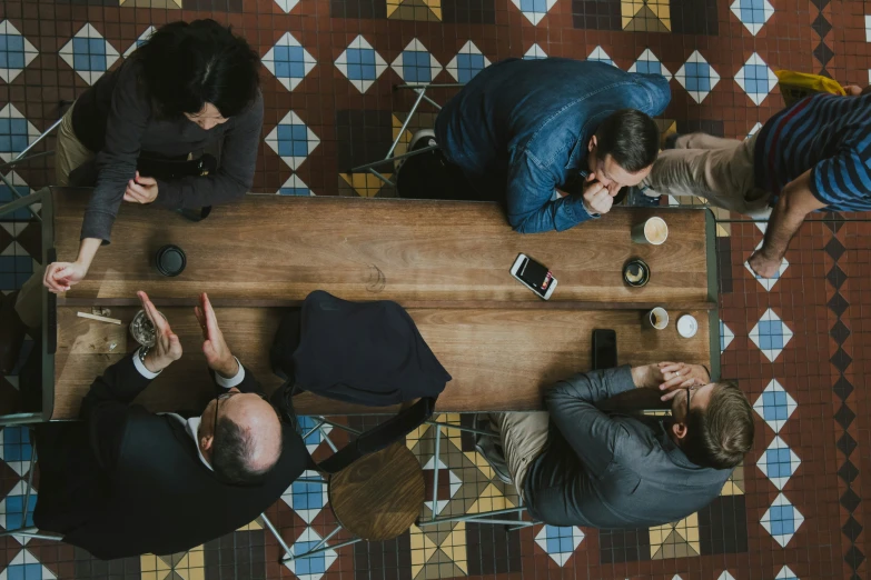 an overhead view shows people at a wood table