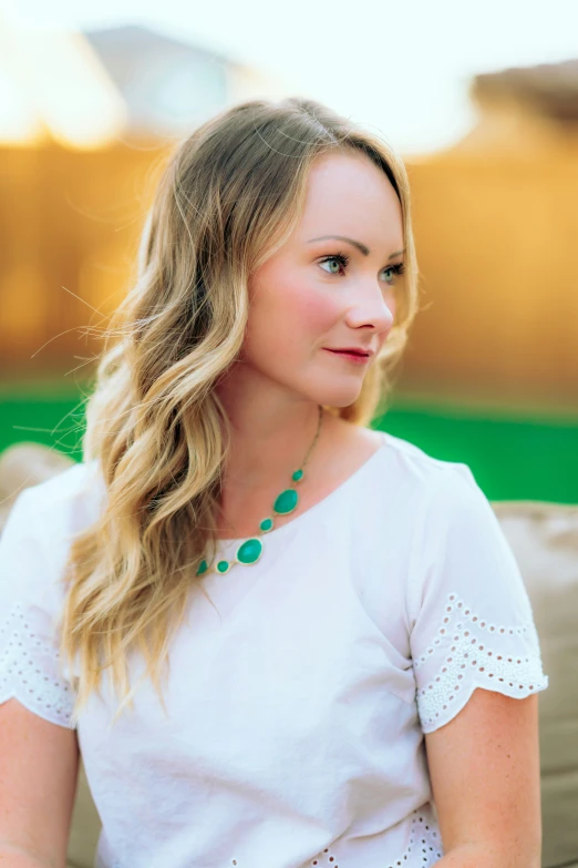 an attractive young woman in white top sitting down