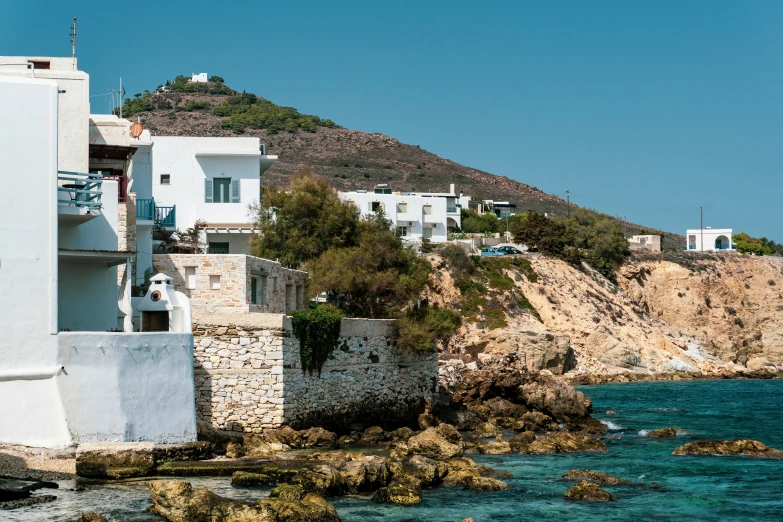 a group of houses sitting on the side of a cliff near a body of water