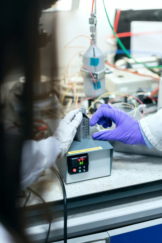 a person in purple gloves touching a device with their hands