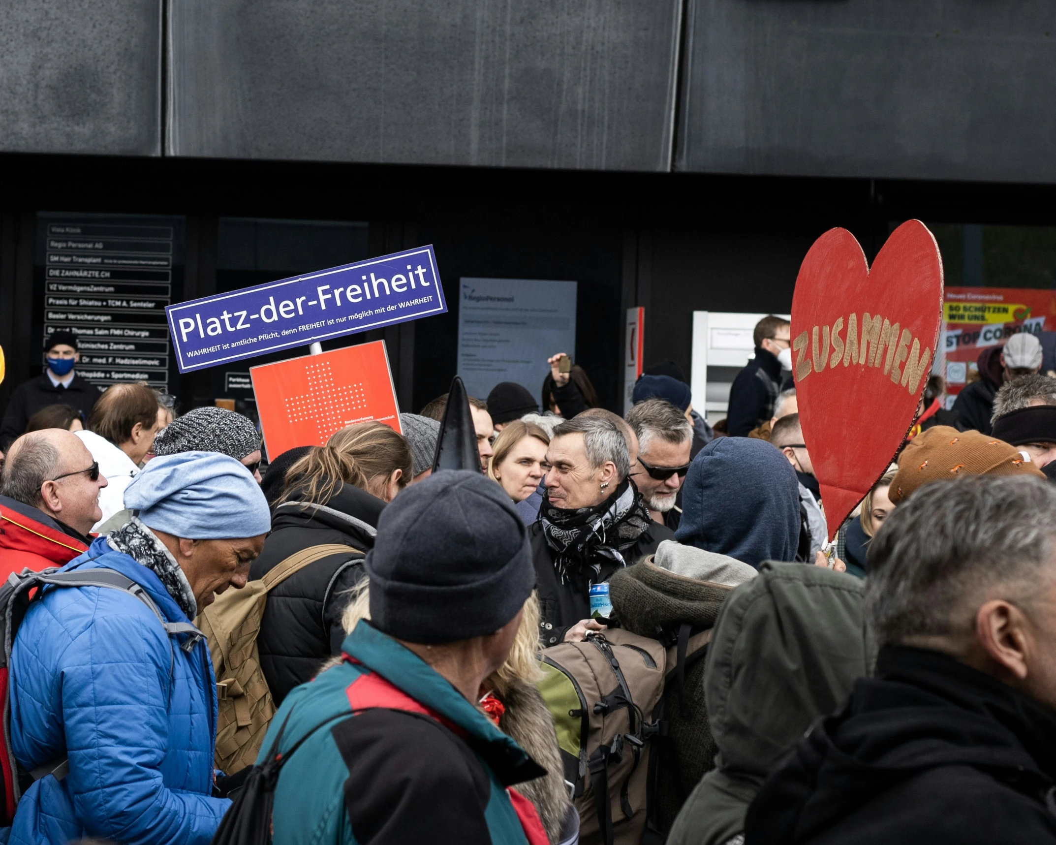 people gathering outside a building in a line with signs reading