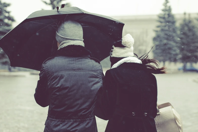 a man and woman stand under an umbrella